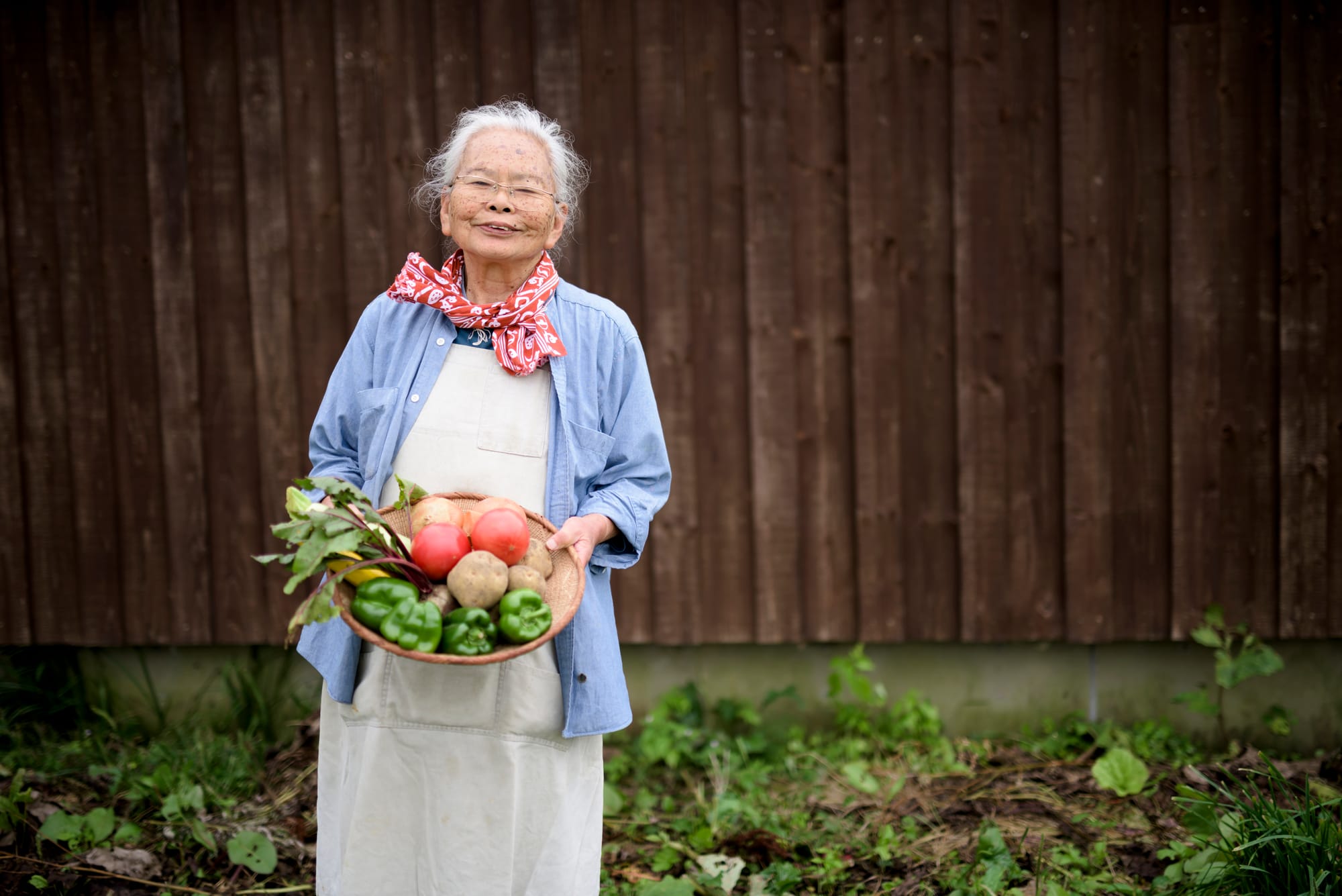 A healthy older woman holding a basket of fruits and vegetables