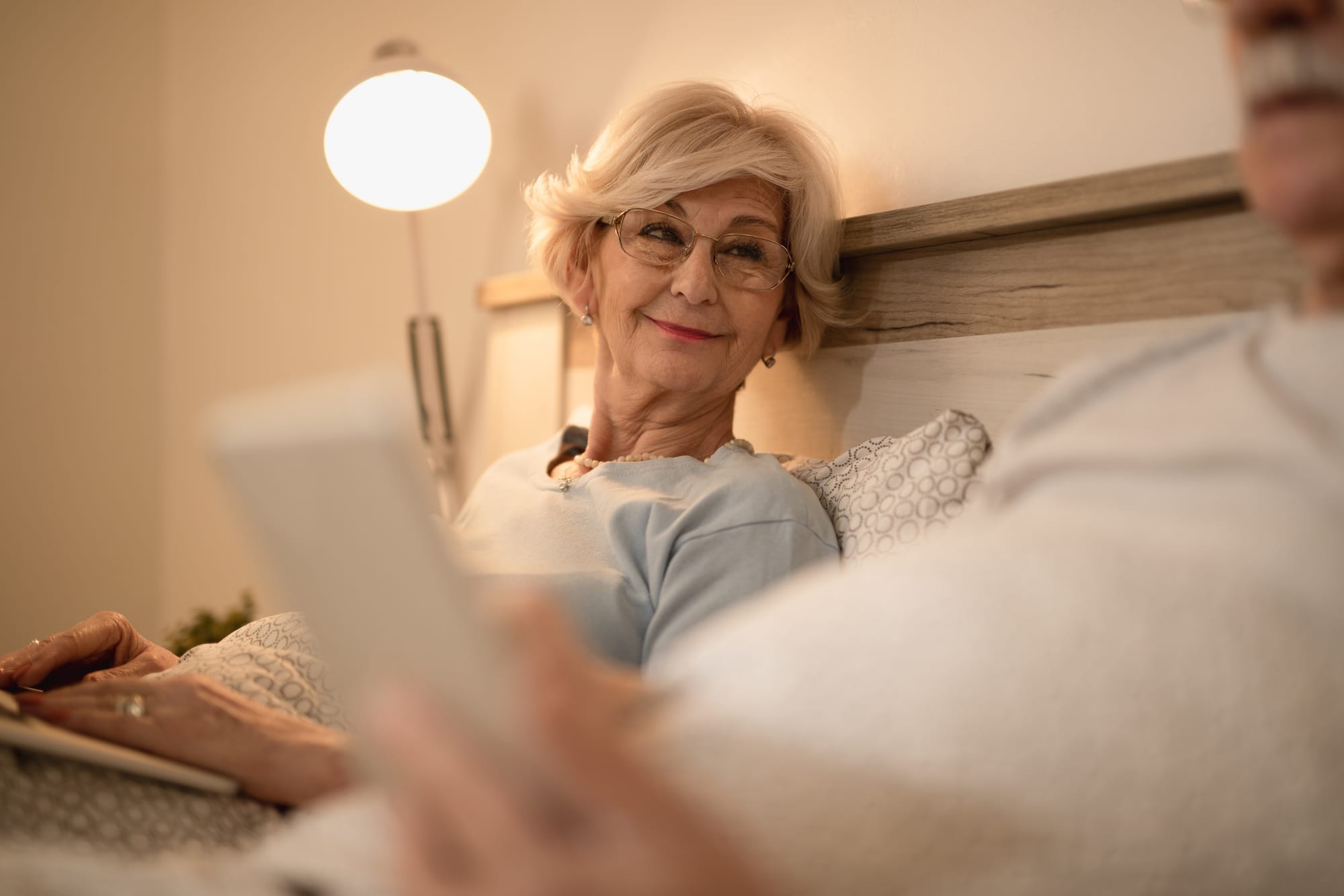 a smiling older woman in a well lit bedroom