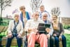 A group of older adults looking at something interesting on an iPad
